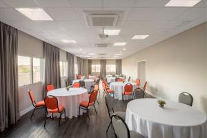 a conference room with white tables and red chairs at Intercity Ribeirão Preto in Ribeirão Preto