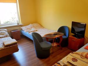 - une chambre avec 2 lits, 2 chaises et une télévision dans l'établissement Pokoje goscinne ''Muszelka'', à Świnoujście