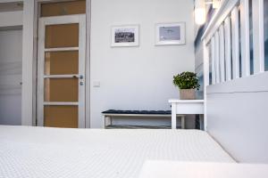 a white bedroom with a door and a bench at Marine Preila in Preila