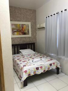 a bedroom with a bed with a floral comforter at Hotel Zagonel in Chapecó
