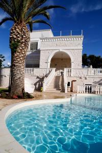 una palmera y un edificio con piscina en Villa Angelina en Selva di Fasano