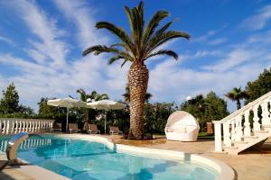 un palmier à côté d'une piscine avec un palmier dans l'établissement Villa Angelina, à Selva di Fasano