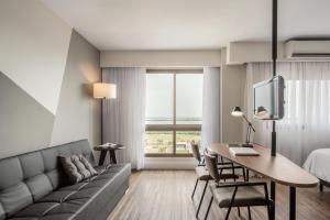 a hotel room with a couch and a desk with a computer at Intercity Porto Alegre Praia de Belas in Porto Alegre