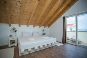 a bedroom with a large white bed with a wooden ceiling at Captain's Attic in Račišće