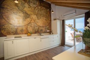 a kitchen with white cabinets and a large wooden wall at Captain's Attic in Račišće