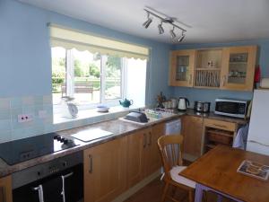 a kitchen with wooden cabinets and a table and a window at Samuel cottage in Caernarfon