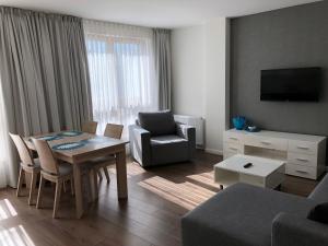 sala de estar con mesa, sillas y TV en Sun Marine, en Władysławowo