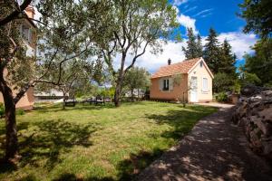 a house with a garden and a grass yard at Kvasina Apartments in Zadvarje