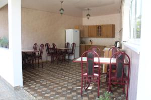 a kitchen with tables and chairs and a refrigerator at Guest House U Aleny in Gagra