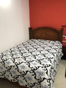 a bedroom with a bed with a black and white comforter at Apartamentos Colonial Home in Quito