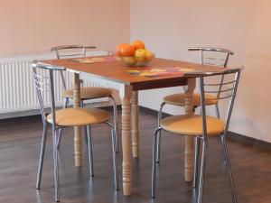 a wooden table with four chairs and a bowl of fruit at Sweet Apartment in Truskavets