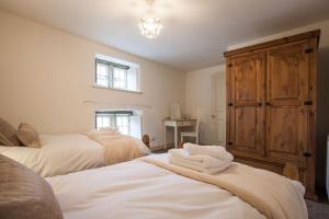 1 dormitorio con 2 camas y armario de madera en Coachmans Cottage, en Stony Middleton