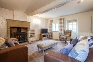 a living room with a couch and a fireplace at Coachmans Cottage in Stoney Middleton