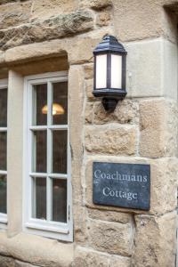 ein Licht an der Seite eines Steingebäudes mit einem Fenster in der Unterkunft Coachmans Cottage in Stony Middleton