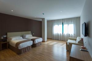 ナロンにあるHotel A Roldanaのベッド2台とソファが備わるホテルルームです。