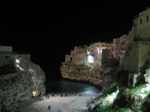 a group of people standing on a beach at night at Versomare in Polignano a Mare