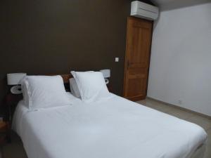 a large white bed with white pillows in a room at Maison d'Hôtes Zella in Bains de Guitera