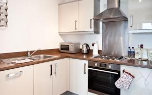 a kitchen with white cabinets and a sink and a microwave at Apartment in Central MK - Bed Choice of 1 Super-king Or 2 Singles and also 2 Sofa Beds - Free Parking and Smart TV - Contractors, Relocation, Business Travellers in Milton Keynes +12 photos