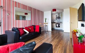 a living room with a black couch and red pillows at Apartment in Central MK - Bed Choice of 1 Super-king Or 2 Singles and also 2 Sofa Beds - Free Parking and Smart TV - Contractors, Relocation, Business Travellers in Milton Keynes