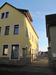 une maison jaune avec une clôture devant elle dans l'établissement Ferienoase, à Pirna