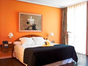 1 dormitorio con 1 cama con pared de color naranja en Hotel Majadahonda, en Majadahonda