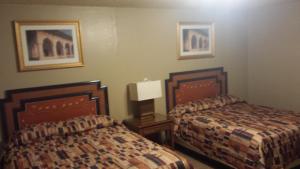 a hotel room with two beds and paintings on the wall at Badlands Hotel & Campground in Interior