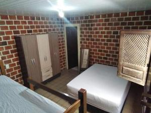 a room with two beds and a brick wall at Casa Centro de Maragogi in Maragogi