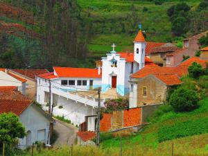 una gran iglesia blanca con techos naranjas en una colina en Casa Eira do Povo, en Vale de Colmeias