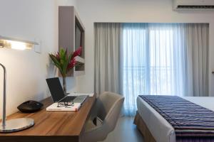 a bedroom with a desk and a laptop on it at Matiz Multi Suites in Duque de Caxias