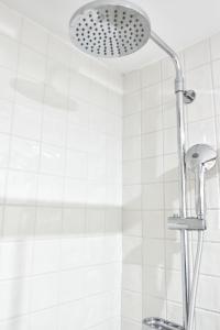 a shower head in a bathroom with white tiles at Mezzanine cozy house in Porto