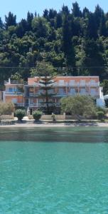 a large pink building on the shore of a beach at Anna Apartments Boukari in Boukari