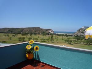 a vase of sunflowers on a balcony with a view at Entre o Mar e a Serra in Maceira