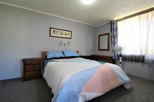 a bedroom with a bed and a dresser and a window at Beachfront 3, 25 Willow Street in Crescent Head
