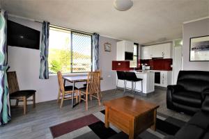 a living room with a table and chairs and a kitchen at Beachfront 3, 25 Willow Street in Crescent Head