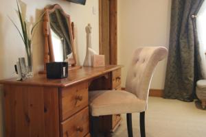 a wooden dresser with a chair and a mirror at Anvil View Guest House in Gretna Green