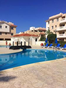 a swimming pool with blue chairs and a building at Pyla Village Resort F110 (Apartment near Larnaca) in Pyla