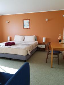 a bedroom with a large bed and a desk and a table at Seaview Norfolk Island in Burnt Pine