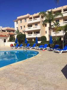 une piscine avec des chaises longues bleues et un bâtiment dans l'établissement Pyla Village Resort F110 (Apartment near Larnaca), à Pýla
