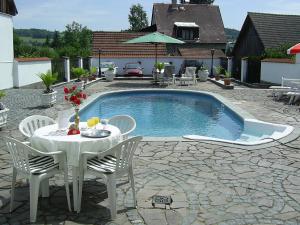 a table and chairs next to a swimming pool at Pension Šejko in Horní Planá