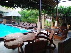 een patio met tafels en stoelen naast een zwembad bij De'dalam 2 Bedroom in Ubud
