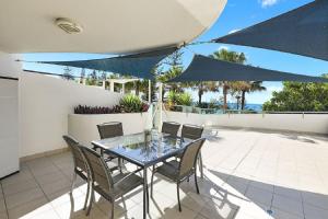 un tavolo e sedie su un patio con ombrelloni blu di Malibu Apartments a Mooloolaba