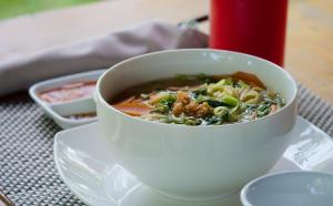 un tazón de sopa en un plato en una mesa en Champa Lodge en Kampot
