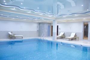 a pool in a hotel with chairs and a swimming pool at Hotel Atlas in Dushanbe