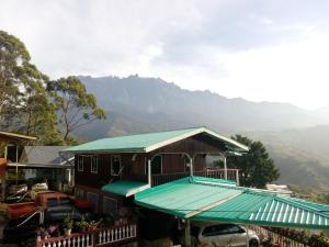 uma casa com um telhado verde com montanhas ao fundo em Almeera Homestay 2 em Kampong Kundassan