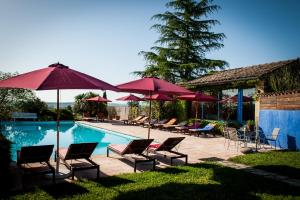 a group of chairs and umbrellas next to a swimming pool at Chambres d'Hôtes et Gîtes Le Mas Bleu & Spa Resort in Rosières