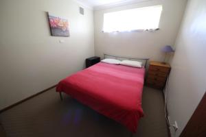 a bedroom with a bed with a red blanket and a window at Stouty's at Hat Head in Hat Head