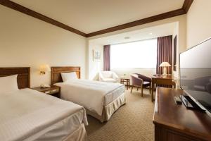 a hotel room with two beds and a flat screen tv at Hotel Tainan in Tainan