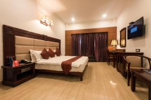 a bedroom with a bed and a desk and a television at Golden Chariot Vasai Hotel in Vasai