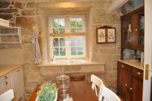 cocina con mesa, fregadero y ventana en Casa tía Amparo, en Portosín