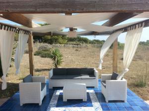 patio con divano e sedie sotto un pergolato di Villetta Cala Rotonda a Favignana